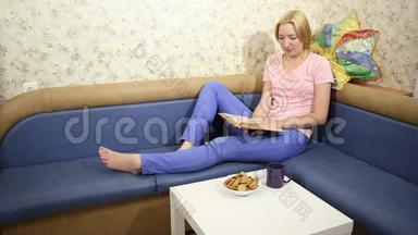 年轻女子坐在沙发上看书喝茶